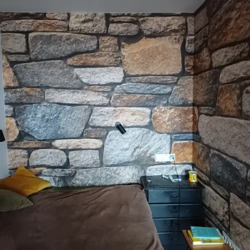 Fototapeta kamień naturalny imitująca kamienny mur za łóżkiem w sypialni
